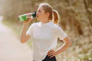 woman in white crew neck t shirt drinking from green plastic bottle
